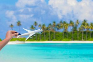 Small white miniature of an airplane on background of turquoise sea